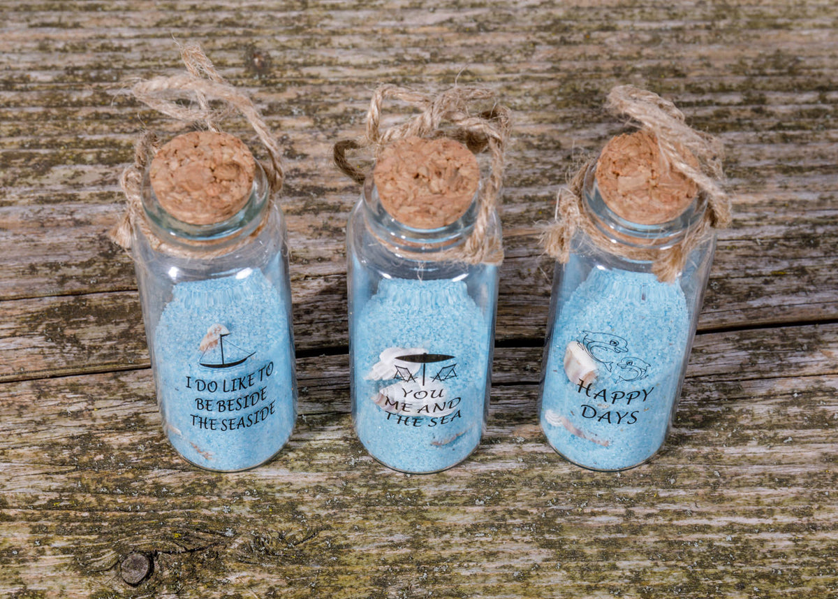 Fläschchen mit blauem Sand und Muscheln
